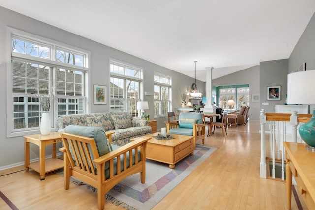 living room featuring vaulted ceiling, plenty of natural light, light hardwood / wood-style floors, and a notable chandelier