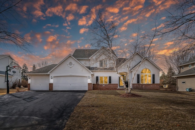 view of front of home featuring aphalt driveway, a yard, brick siding, and an attached garage