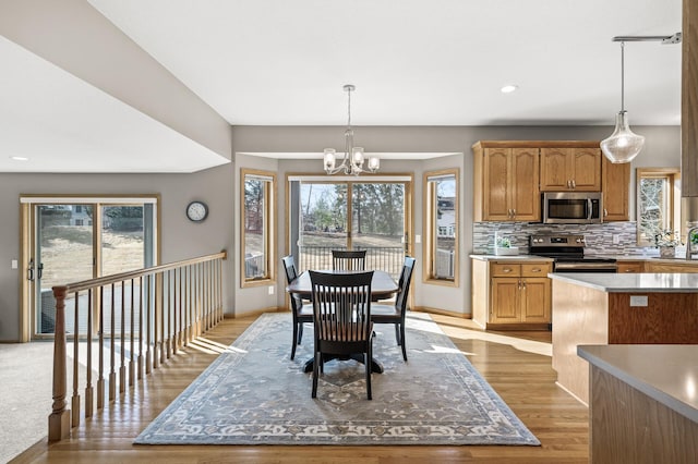 dining area with recessed lighting, baseboards, a notable chandelier, and light wood-style flooring