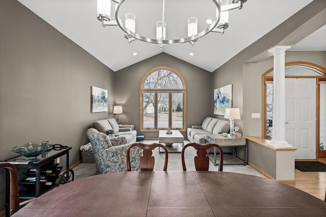 living area with baseboards, an inviting chandelier, decorative columns, vaulted ceiling, and light wood-type flooring