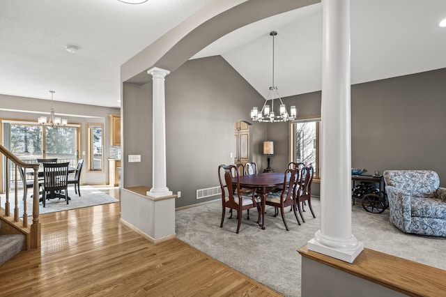 dining room featuring visible vents, light wood finished floors, lofted ceiling, decorative columns, and a chandelier