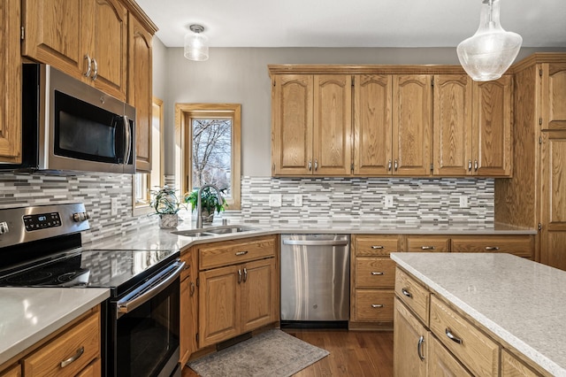 kitchen featuring dark wood finished floors, a sink, decorative backsplash, light countertops, and stainless steel appliances