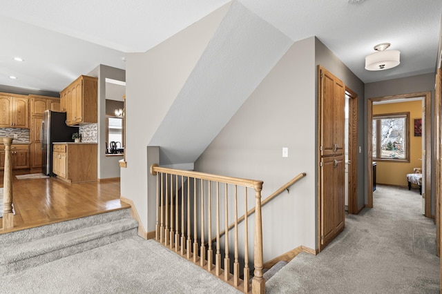 hallway with recessed lighting, an upstairs landing, light colored carpet, and baseboards