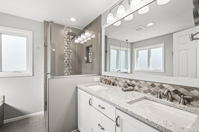 full bath featuring double vanity, visible vents, a shower stall, and a sink