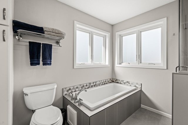 full bathroom featuring baseboards, toilet, and a bath