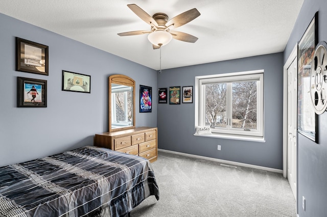 bedroom featuring light carpet, a textured ceiling, baseboards, and a ceiling fan