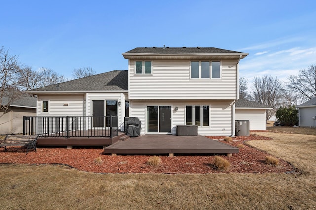 back of property featuring a wooden deck, a yard, and a shingled roof