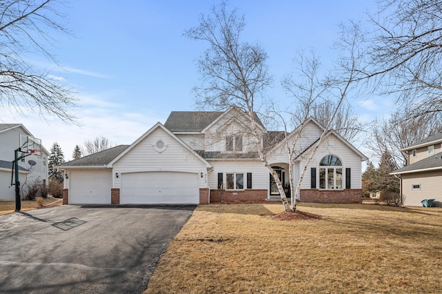 view of front of property with aphalt driveway, brick siding, a garage, and a front yard