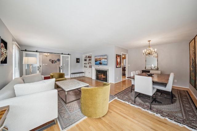 living room featuring a notable chandelier, a barn door, and wood-type flooring