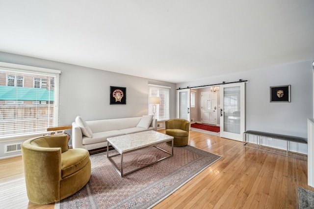 living room featuring a wealth of natural light, a barn door, and light hardwood / wood-style floors