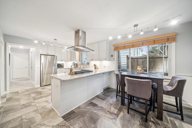 kitchen with stainless steel refrigerator, island range hood, white cabinets, kitchen peninsula, and pendant lighting