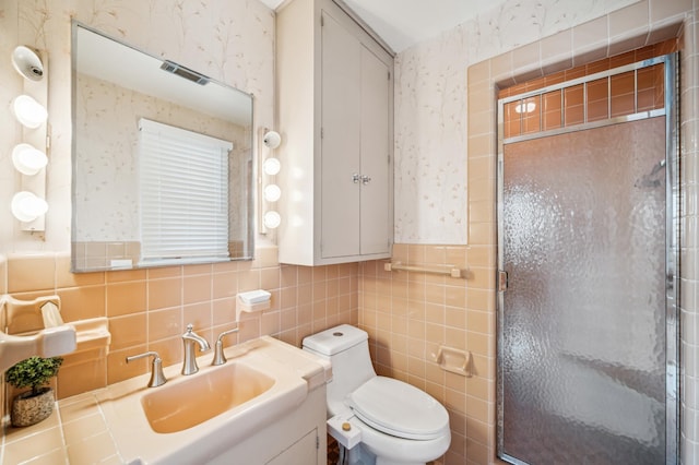 bathroom with tile walls, toilet, a shower with door, and vanity