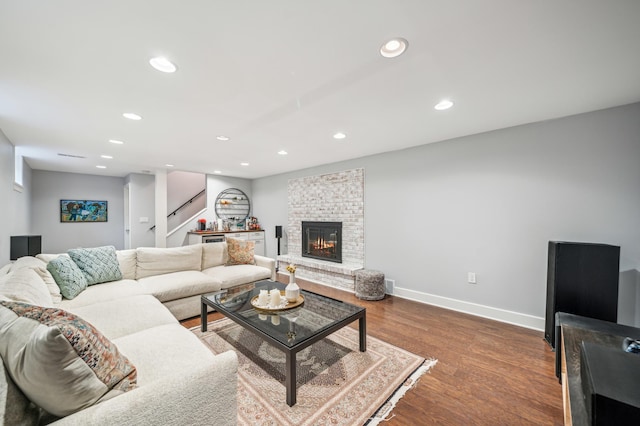 living room with a brick fireplace and wood-type flooring