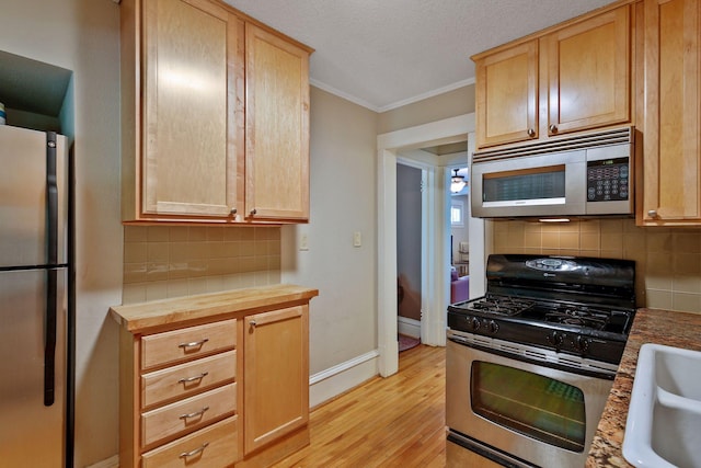 kitchen with light hardwood / wood-style floors, light brown cabinetry, and appliances with stainless steel finishes