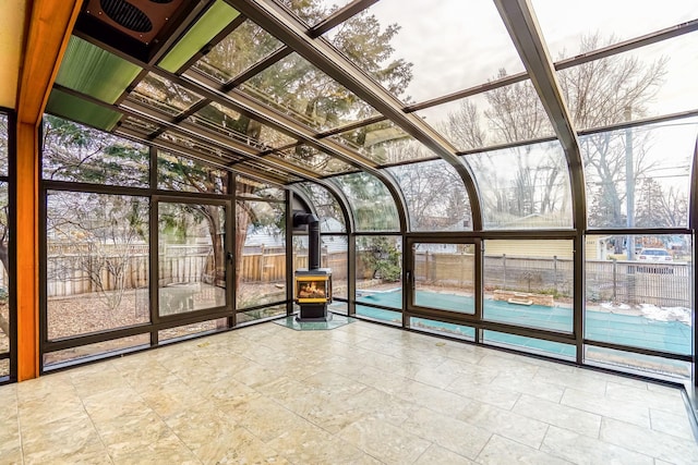 unfurnished sunroom with a wood stove and a healthy amount of sunlight