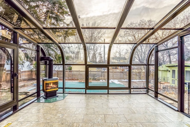 unfurnished sunroom with plenty of natural light and a wood stove