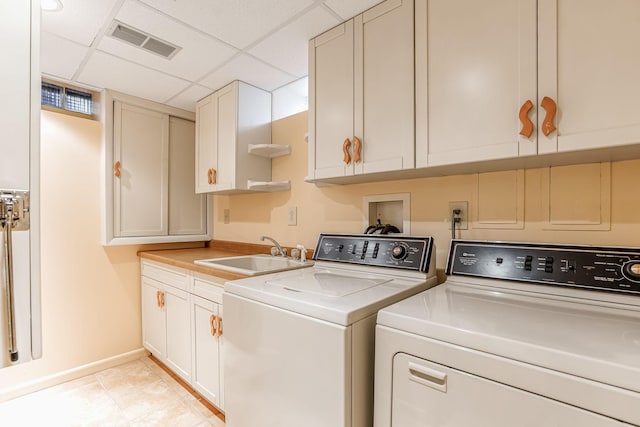 clothes washing area with cabinets, washing machine and dryer, and sink