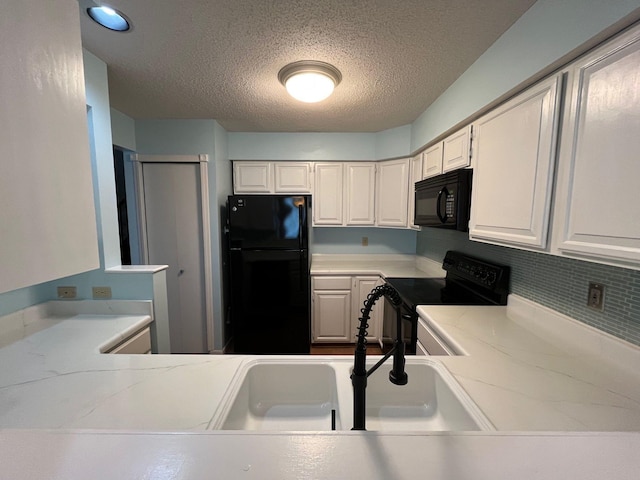 kitchen featuring a textured ceiling, tasteful backsplash, white cabinetry, and black appliances