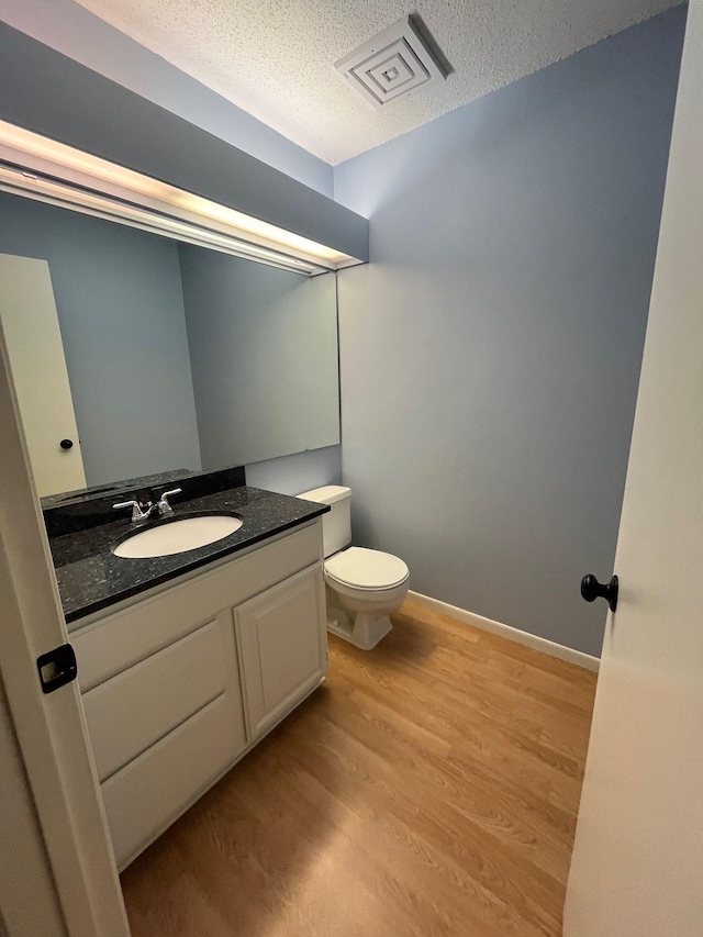 bathroom featuring hardwood / wood-style flooring, vanity, toilet, and a textured ceiling