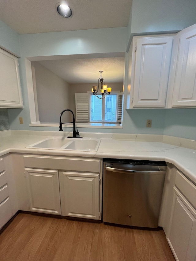 kitchen featuring pendant lighting, white cabinets, sink, stainless steel dishwasher, and a chandelier