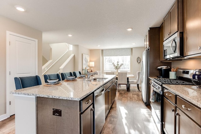 kitchen featuring a center island with sink, sink, a breakfast bar area, light hardwood / wood-style flooring, and stainless steel appliances