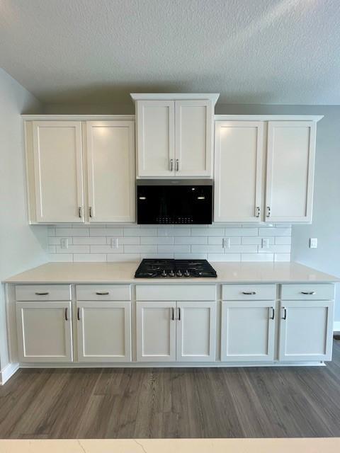 kitchen with dark wood-type flooring, white cabinetry, and gas cooktop