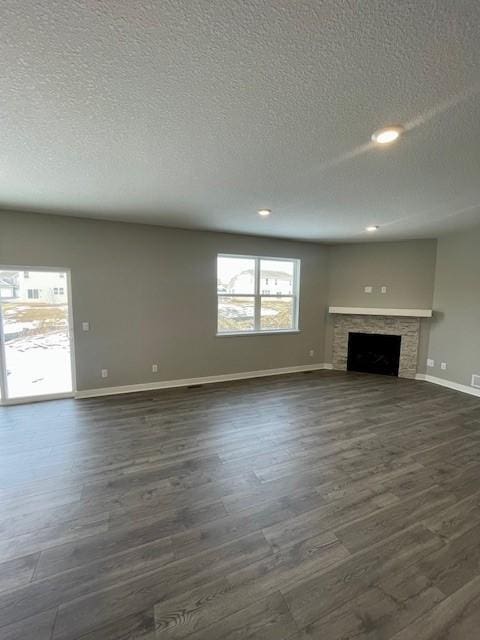 unfurnished living room with a textured ceiling, dark wood-type flooring, a fireplace, and baseboards