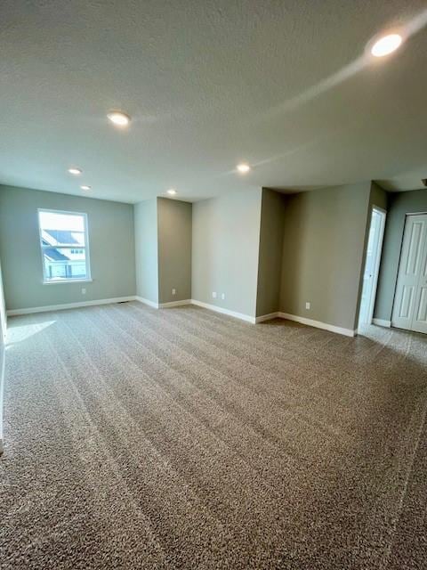 below grade area with a textured ceiling, recessed lighting, carpet, and baseboards