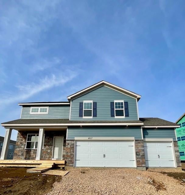 view of front facade featuring a garage, stone siding, and a porch