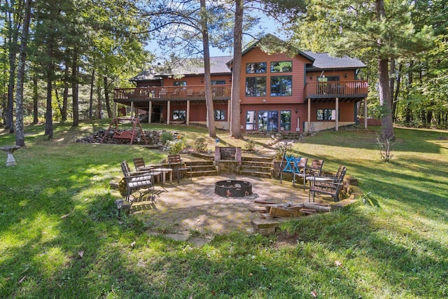 back of property with a lawn, a patio, a deck, and an outdoor fire pit