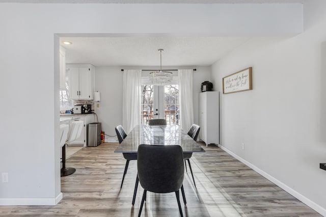 dining room featuring light wood-type flooring, french doors, and a textured ceiling