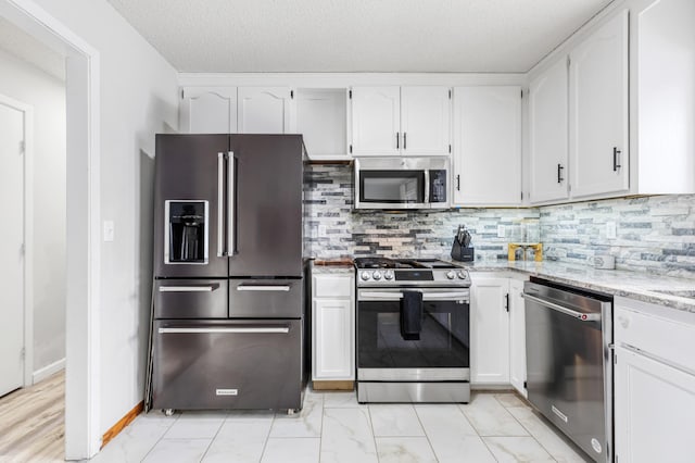 kitchen featuring stainless steel appliances, light stone countertops, white cabinets, and backsplash