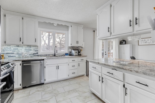 kitchen with sink, white cabinetry, stainless steel appliances, and light stone counters