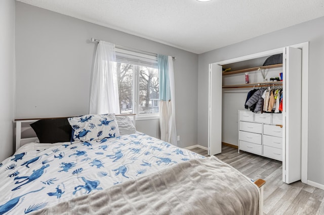 bedroom featuring light hardwood / wood-style flooring, a textured ceiling, and a closet