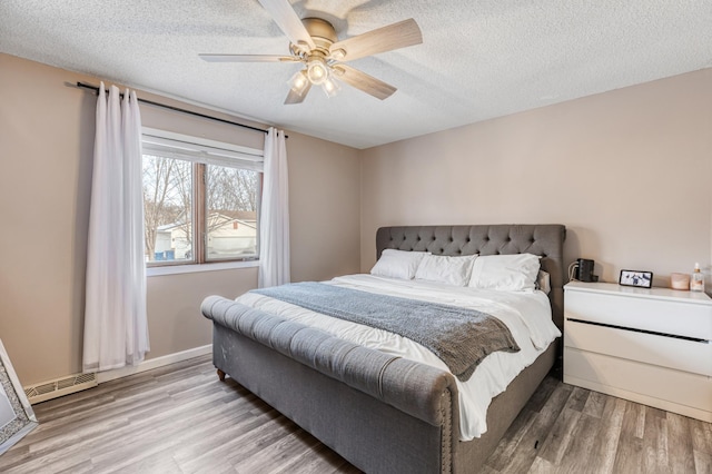 bedroom with ceiling fan, light hardwood / wood-style flooring, and a textured ceiling