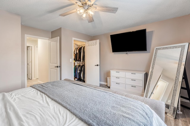 bedroom featuring a closet, ceiling fan, wood-type flooring, a textured ceiling, and a spacious closet