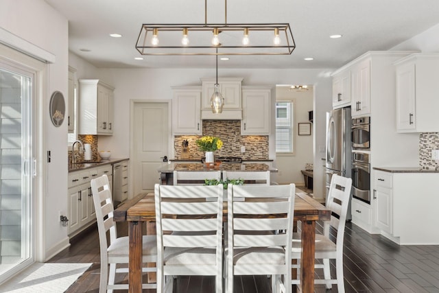 kitchen featuring appliances with stainless steel finishes, dark wood-type flooring, a sink, and a center island