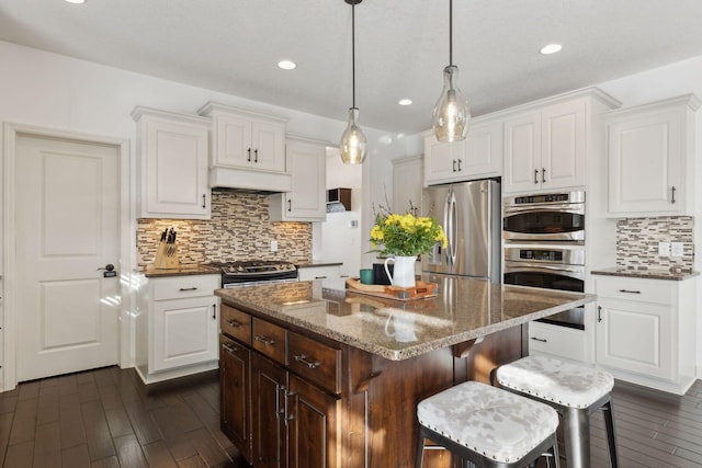 kitchen with stainless steel appliances, dark wood-style flooring, white cabinets, and a kitchen island