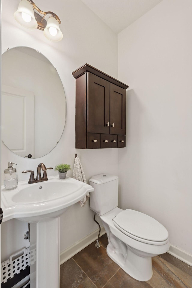 half bath featuring baseboards, a sink, toilet, and wood finished floors