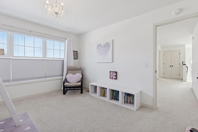 living area with an inviting chandelier, carpet, baseboards, and a textured ceiling