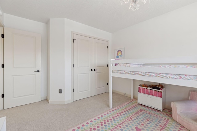 bedroom featuring carpet, a closet, a textured ceiling, and baseboards