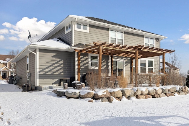 snow covered rear of property with a pergola