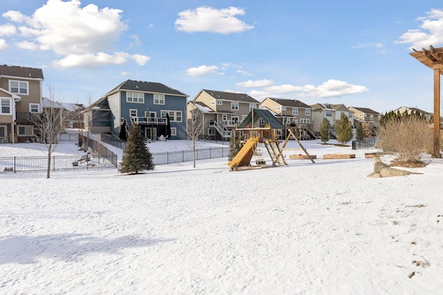 snow covered playground featuring a residential view, fence, and a playground