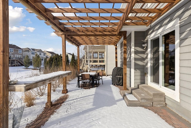 snow covered patio featuring entry steps, outdoor dining area, area for grilling, a residential view, and a pergola