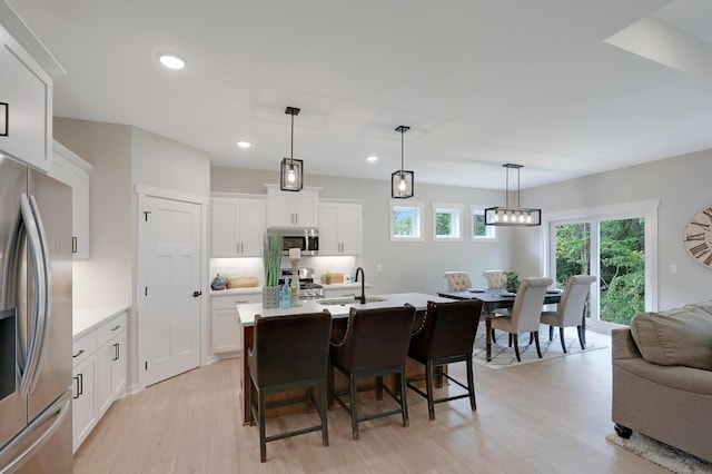 kitchen featuring sink, backsplash, pendant lighting, white cabinets, and appliances with stainless steel finishes