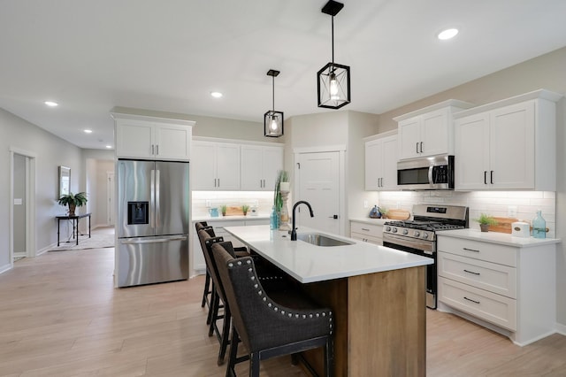 kitchen featuring white cabinets, appliances with stainless steel finishes, an island with sink, and sink