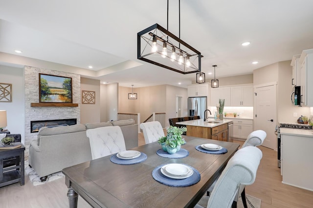 dining area featuring light hardwood / wood-style flooring, a stone fireplace, and sink