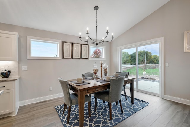 dining area with an inviting chandelier, vaulted ceiling, and light hardwood / wood-style flooring