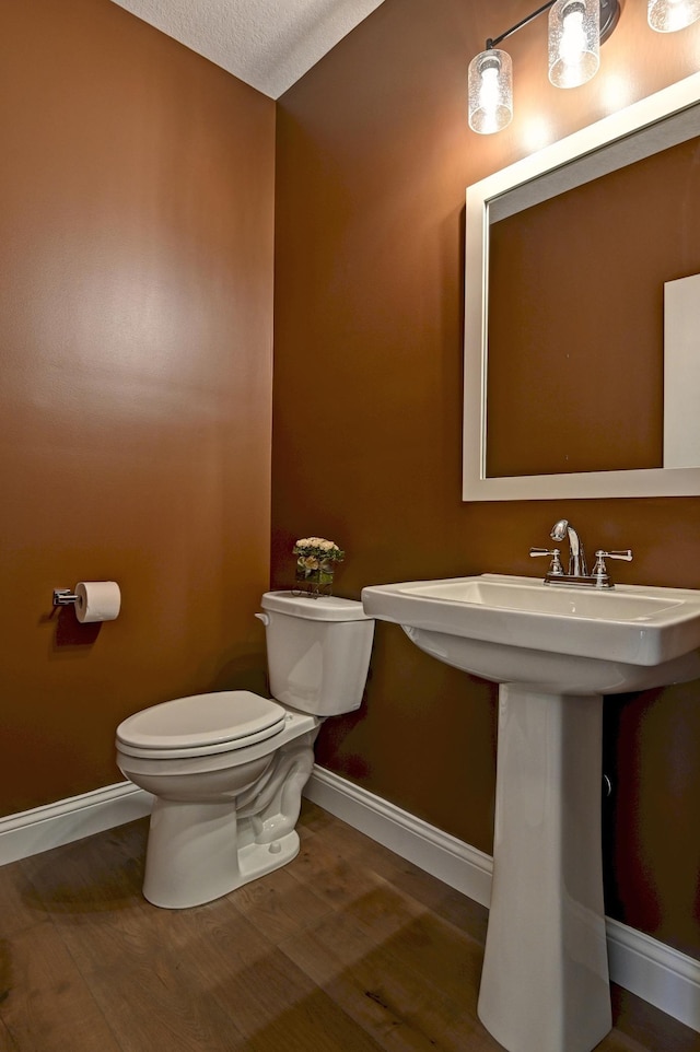 bathroom with wood-type flooring, a textured ceiling, toilet, and sink