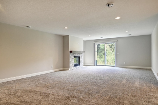 unfurnished living room with a stone fireplace and carpet